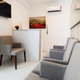 Small waiting room with reception desk, chairs and wall art in grey and
white tones